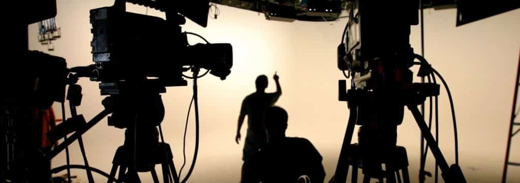 A film director on set, watching as a scene plays out
