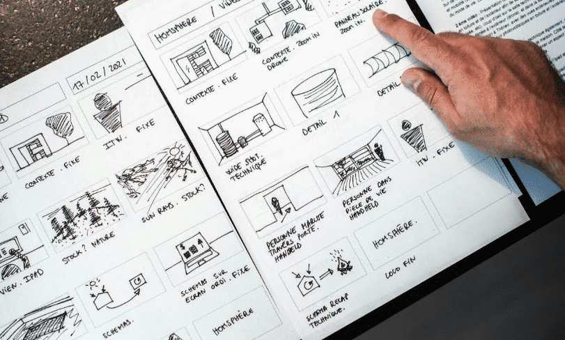 A hand pointing at a panel of a hand-drawn storyboard for a movie.