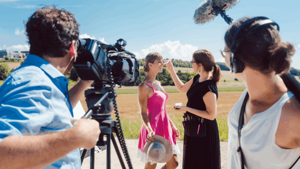 a film crew on set. Makeup touches up the actress's face