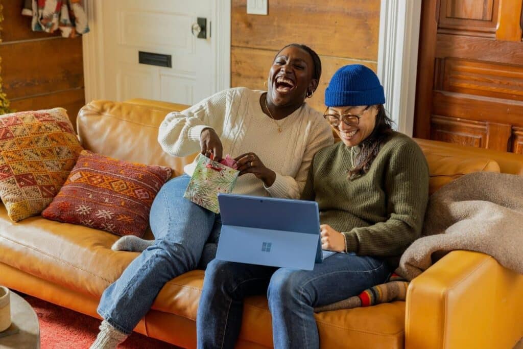 Two people laughing while looking at a laptop screen - maybe a skit or screenplay written with Celtx - often misspelled as "Celtex" in searches.