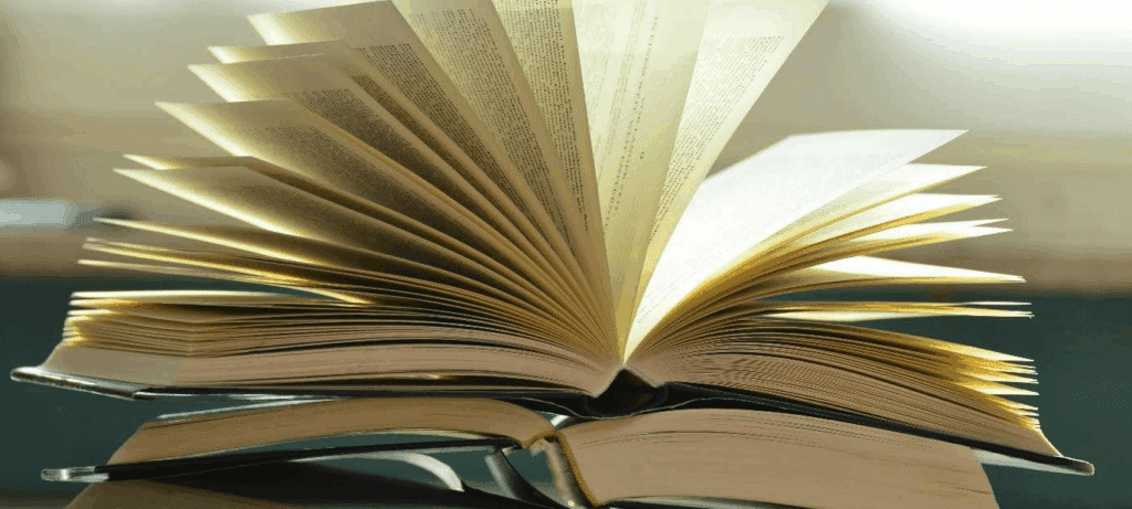 A stack of books, the one on top is open.