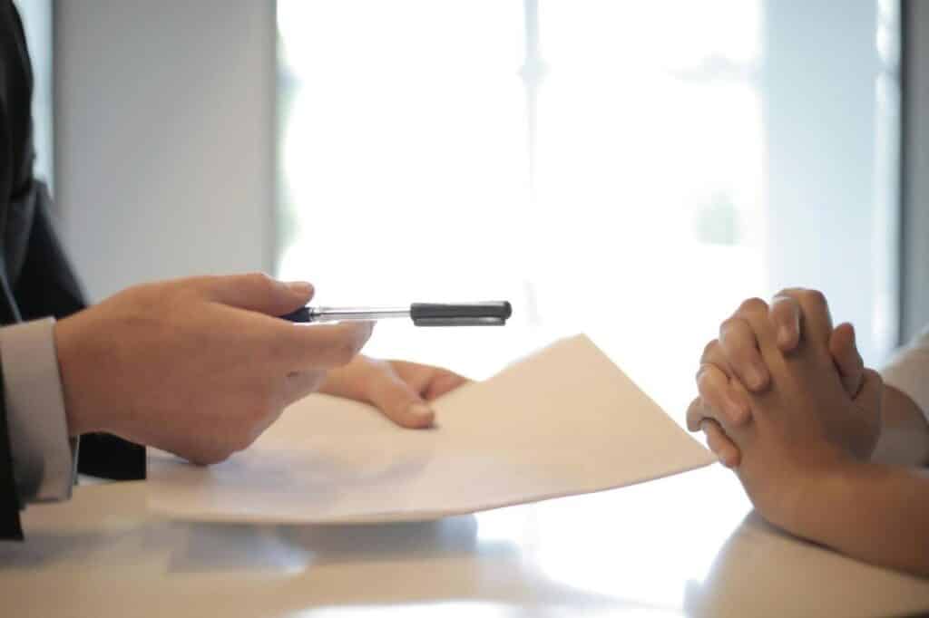 Close up shot of a screenwriting contract being handed to the screenwriter.
