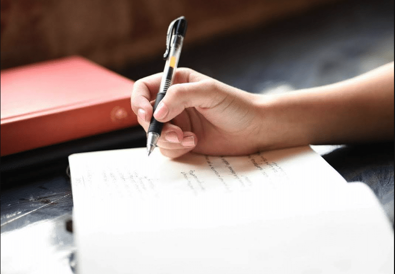 a woman's hand writing notes in a notebook. Streamline your scriptwriting with Celtx screenwriting software.