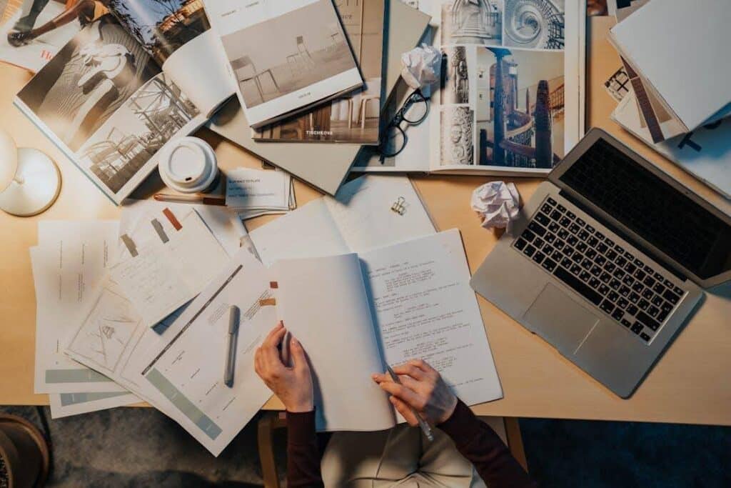 A person sits at a cluttered desk, editing a script