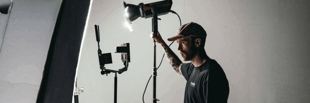 Man with a beard on a film set holding a light