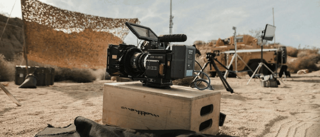 a camera sits on a box in the center of what appears to be a film set in the desert