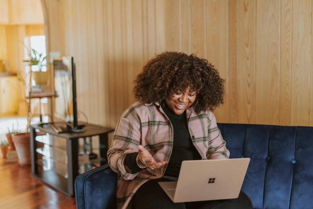 A woman smiling while looking at her open laptop.