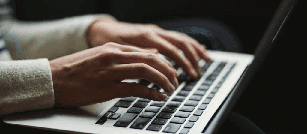 close-up photo of hands typing on a laptop's keyboard