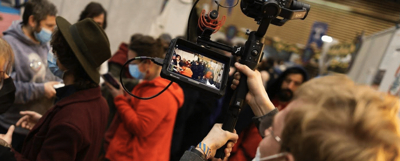The viewfinder of a camera filming a group of people wearing medical masks (probably a covid-era photo)