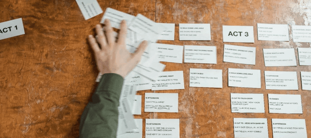 overhead photo of a showrunner reorganizing story beats on notecards