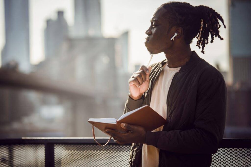 A man looks out over the city, brainstorming ideas with a notebook in his hand.