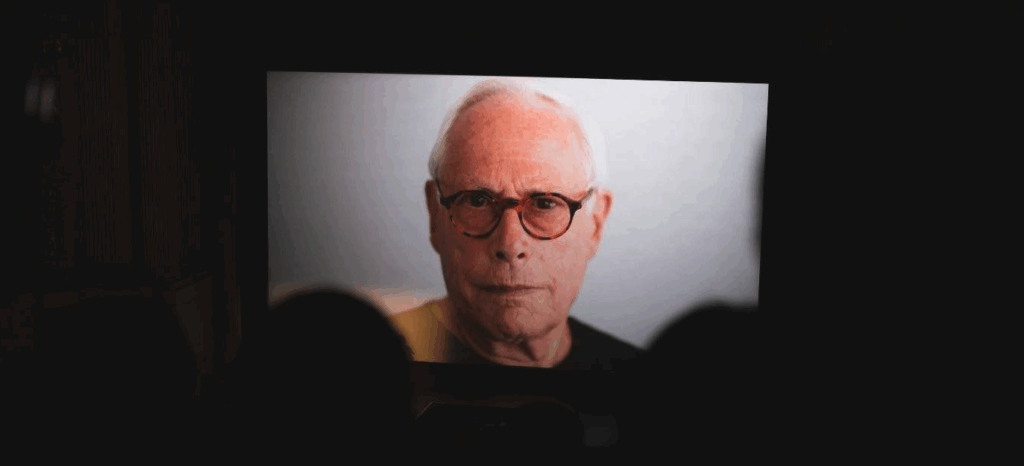 A dark theater full of people watching a documentary film