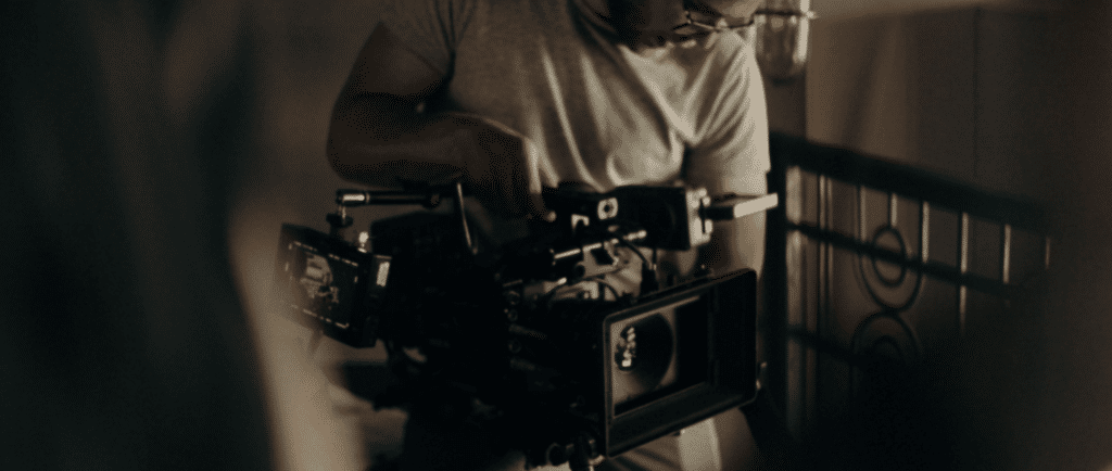 A cameraman working with a camera, most likely on an indie film set.