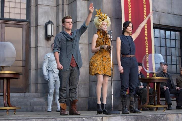 The Hunger Games: Katniss and Peeta stand on stage. An example of Character vs. Society external conflict.