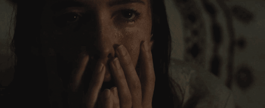 A close-up of a woman's face, tears glinting in the light - from the horror genre film: The Night House