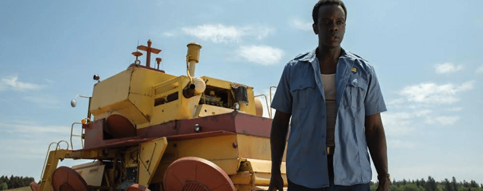 A man stands in front of a floating tractor (or something that looks like a floating tractor) in the sci-fi series Tales From the Loop