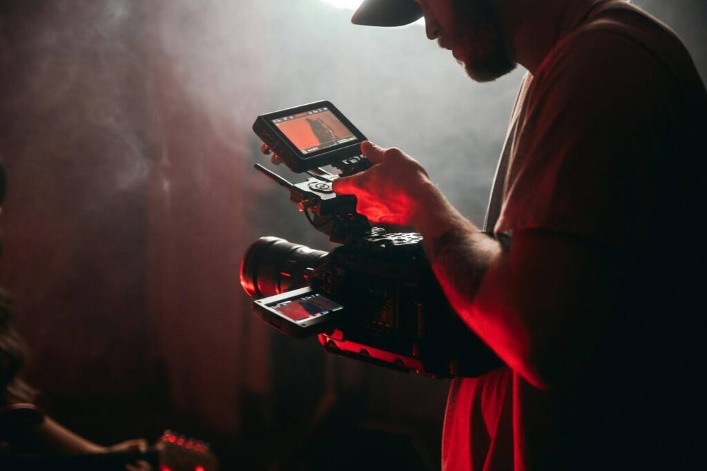 A man on set setting up his camera for a shot. He peers into the screen to make sure his camera shot is perfect.