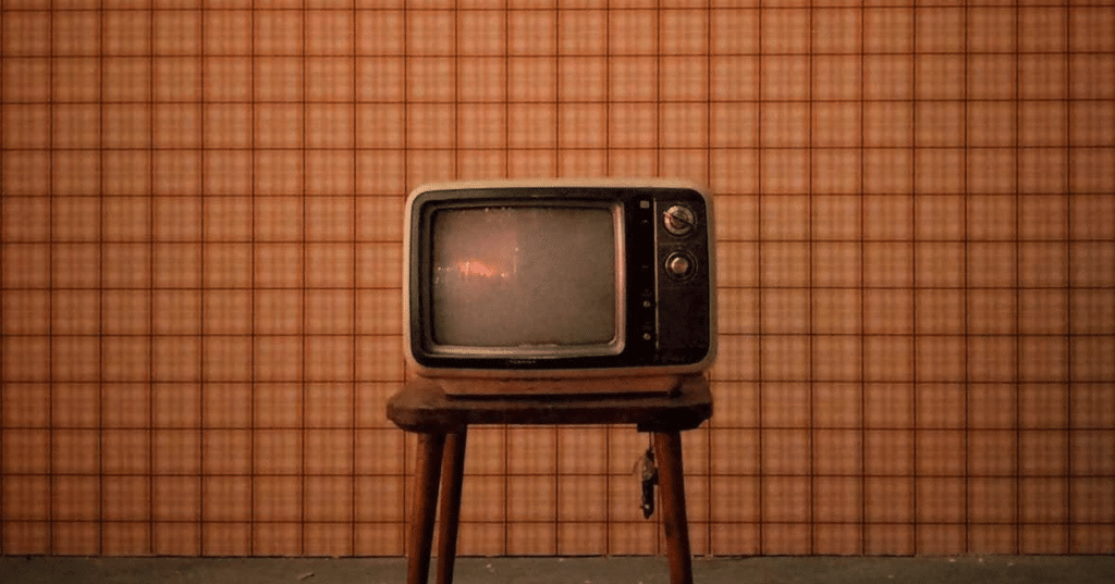 A photo of an old tv in front of an orange checkered background. Write your tv pilot or episodic script with celtx script writing software.