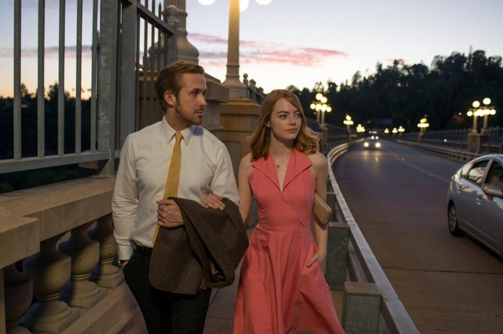 A still from the film La La Land showing Ryan Gosling and Emma Stone walking down the street together. This is being used as an example of resolution in storytelling and film.