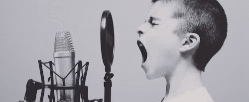 A young child yells into an old-fashioned microphone. AI in film.