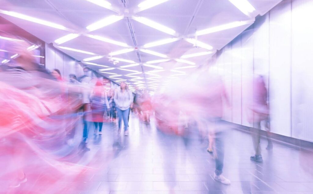 A sped up timelapsed photo of people walking down a hallway (possibly an airport)