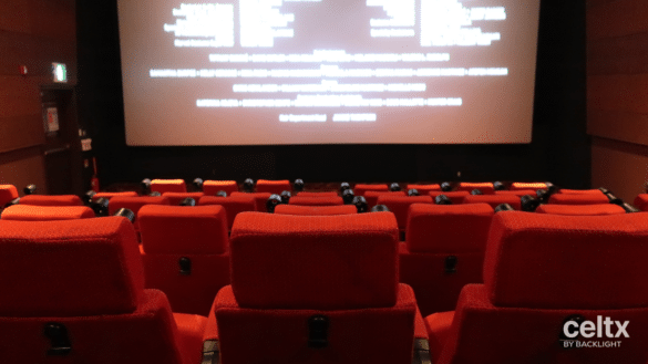 The end credits of a film roll on a movie theater screen