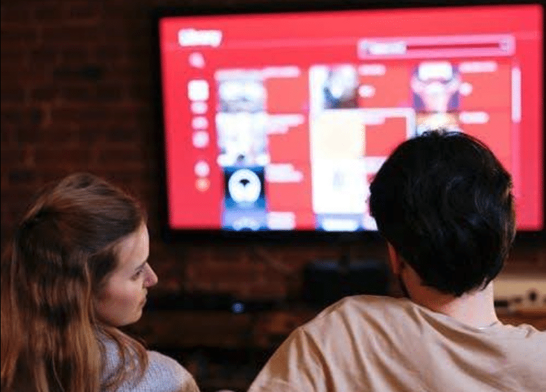 Two people watching television from their couch.