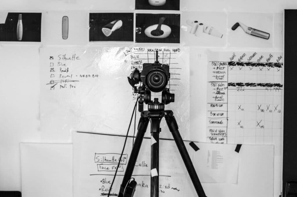 A camera on a tripod in front of storyboards and schedules