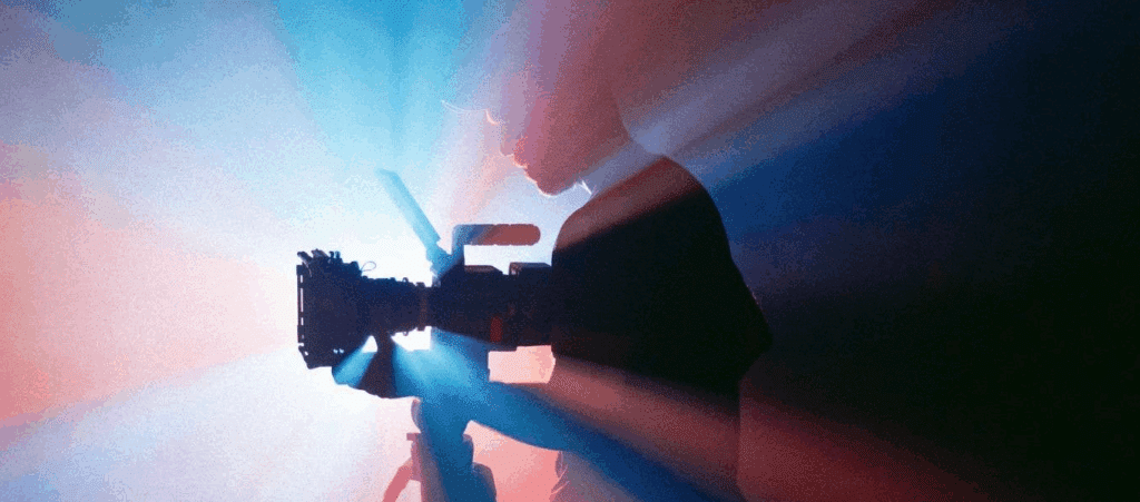an artistic backlit photo of a man holding a film camera