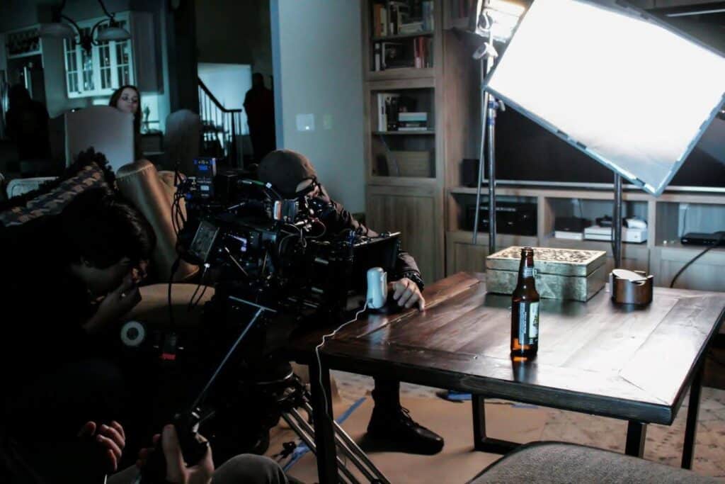 Maybe this is a photo of a the shoot from a beer ad, because there's a film crew filming a single beer bottle on a coffee table.