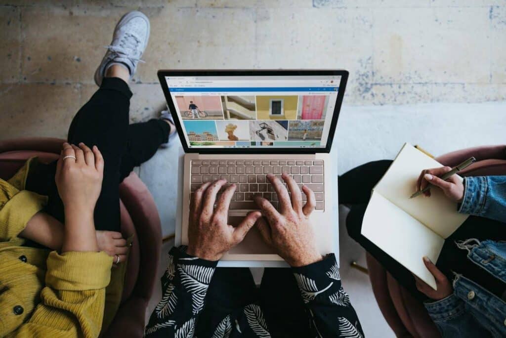 A couple of people using a laptop - it appears to have Canva or Adobe stock open.