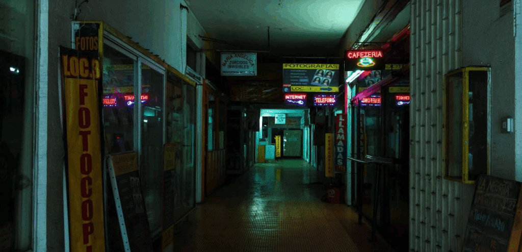 A dingy hallway filled with shops, like a photography place and a cafeteria.