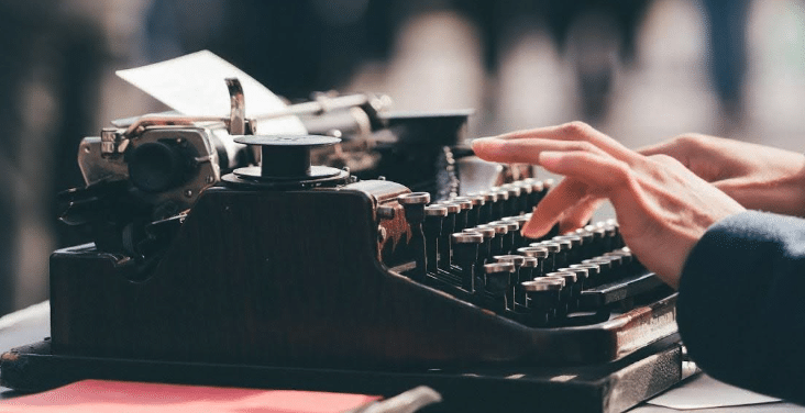 zoomed in on hands typing on an old typewriter