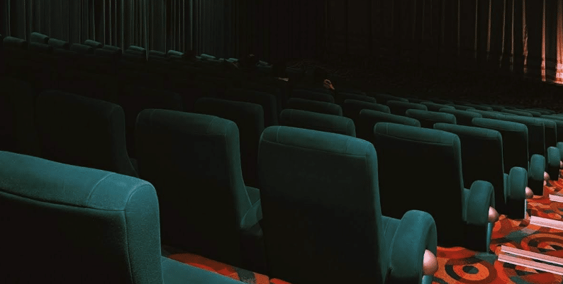 empty rows of plush seats in a movie theater.