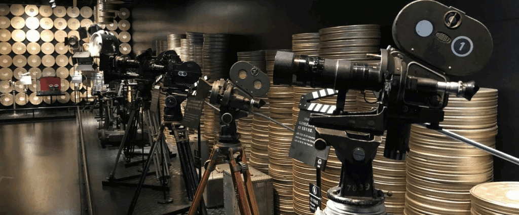 A row of film cameras from different eras surrounded by old film canisters