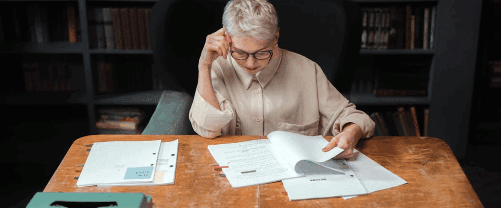 a woman sits behind a desk, reading through a movie script.