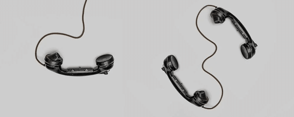 some old black telephones lying on a white surface