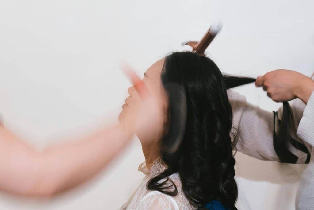 a woman with dark hair gets her hair and makeup done by the wardrobe and makeup teams
