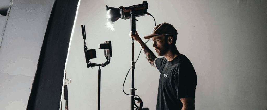 A gaffer mans a tall light on set