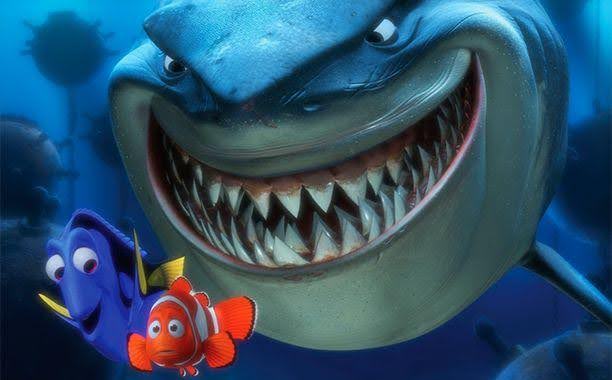 Bruce the shark smiles behind Dory and Marlin
