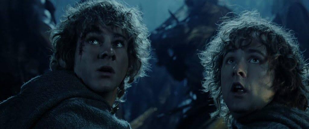 Two Hobbits look up at something much taller than them