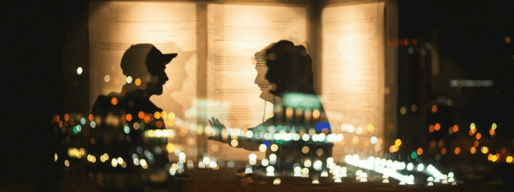 two people's silhouettes who are deep in conversation, seen through reflective glass