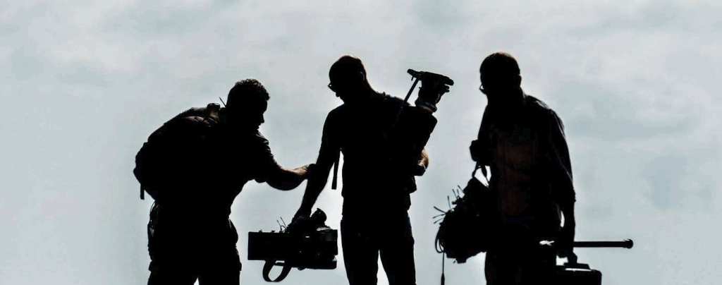 A silhouetted film crew on a beach