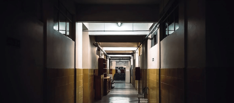 a long, empty, dimly-lit hallway - looking pretty spooky.