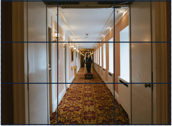 an example of leading lines + rule of thirds. A man pushes a cart down a hotel hallway