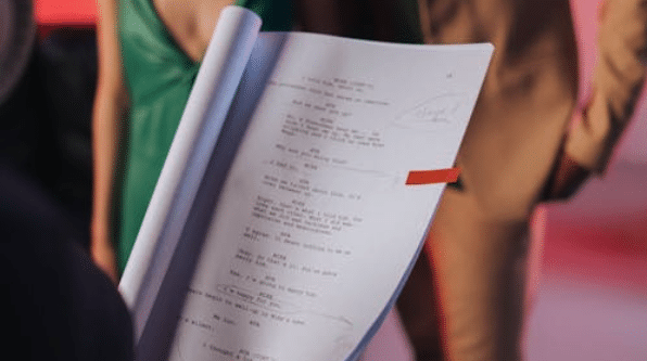 someone holding a screenplay marked up and turned to a specific page/scene