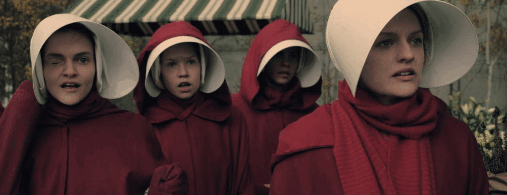 Offred, Janine, and two other Handmaids in their red uniforms - in The Handmaids Tale (Hulu) - based on the dystopian novel by Margaret Atwood.