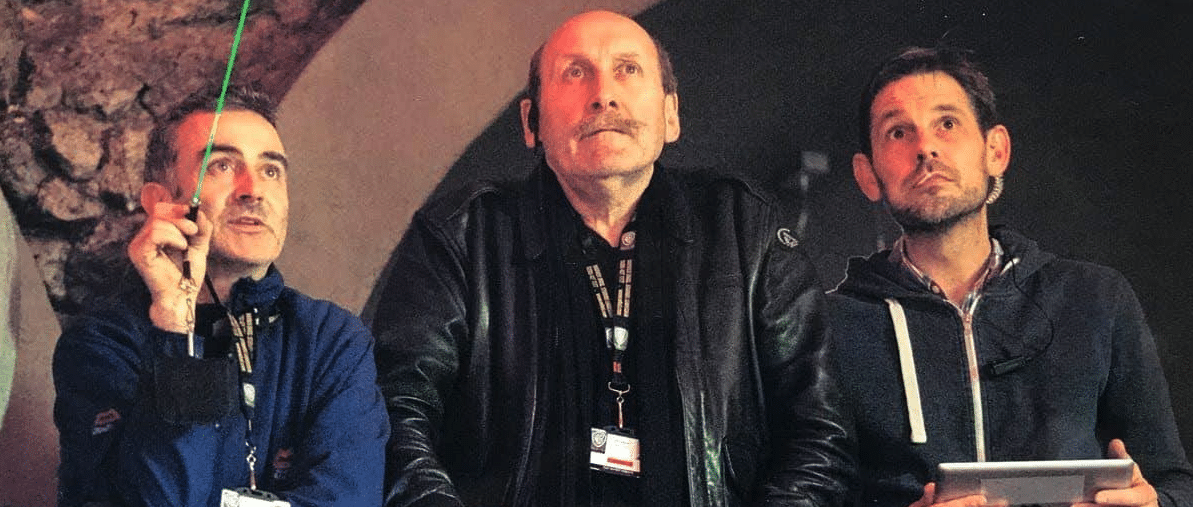 Well-known Gaffer John Higgins is seen standing between two other men, all looking up.