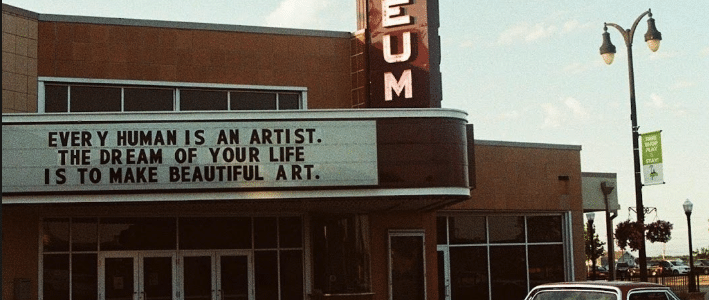 The front of the orpheum theater. The marquee reads: Every human is an artist. The dream of your life is to make beautiful art.