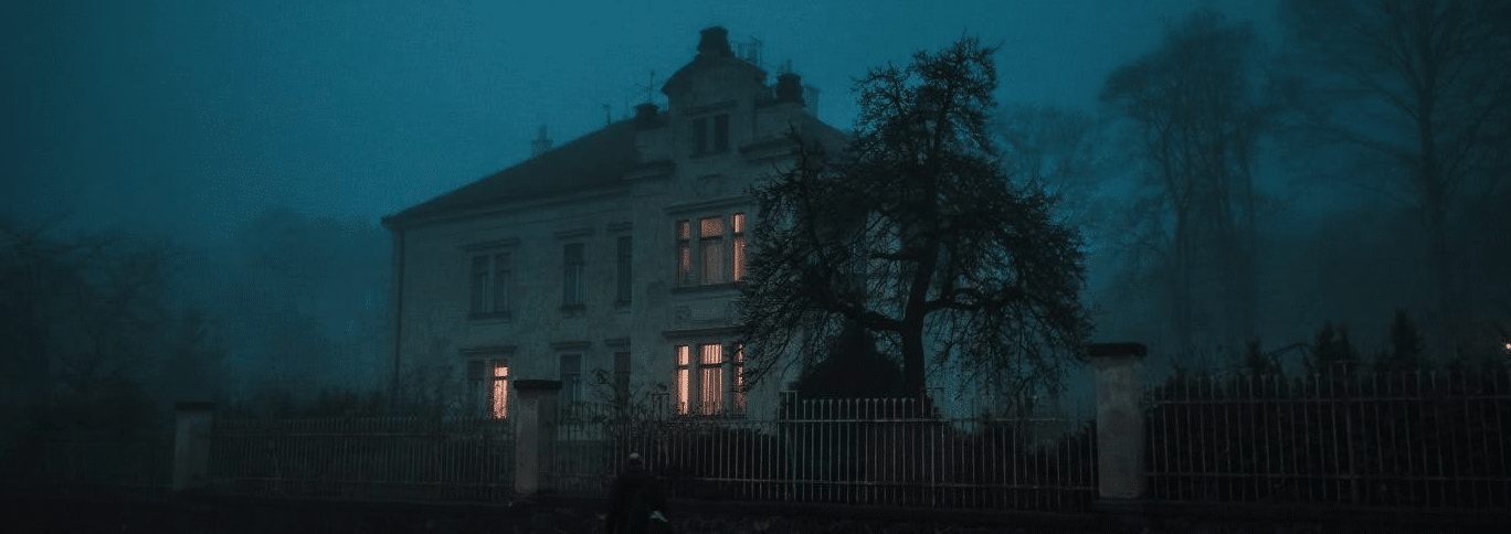 a creepy old mansion in the dark with a few lights on. horror archetypes